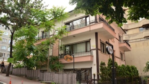 A multi-story building with balconies, a sign indicating a restaurant, and a gated entrance.