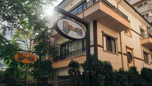 A hostel with a signboard, balconies, and a gated entrance.