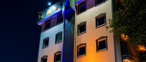 A multi-story hotel with a prominent entrance, illuminated signage, and a vertical light feature.