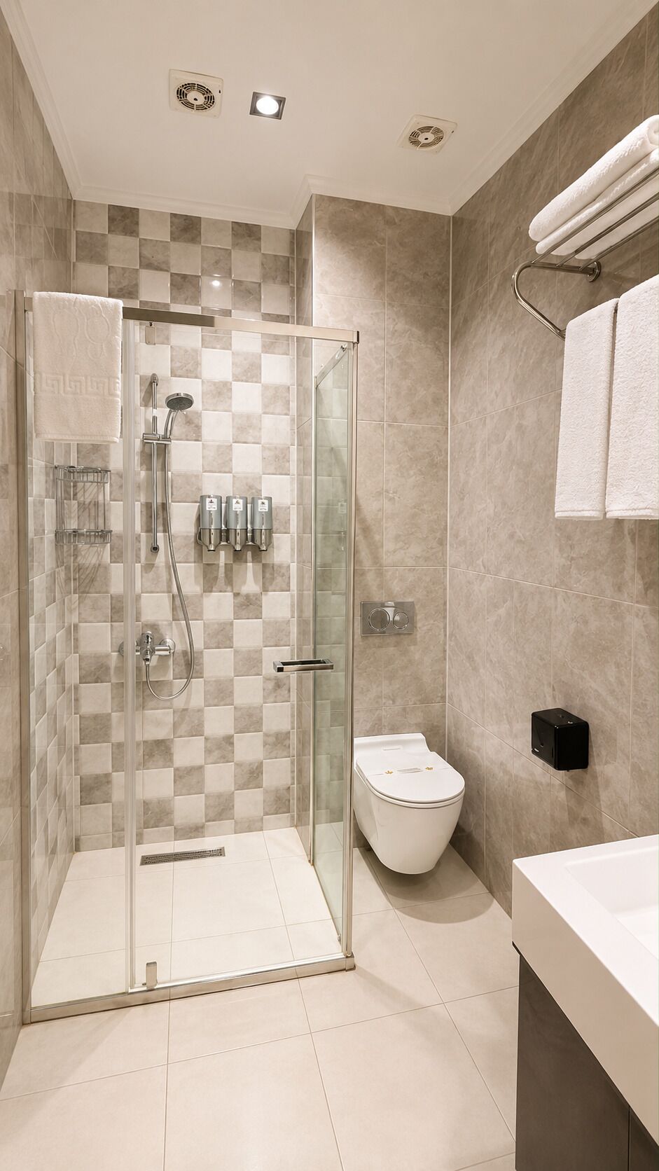 Une salle de bain moderne dotée d’une douche à parois de verre, de toilettes et d’un espace lavabo.