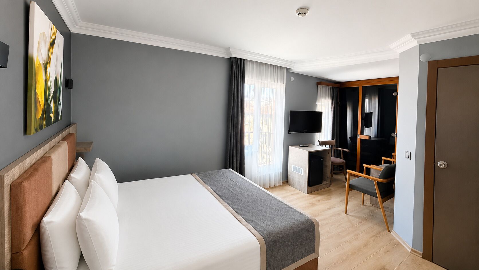 Una habitación de hotel con cama, escritorio con televisor, silla y puerta.