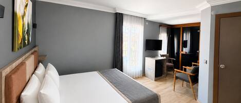 Una habitación de hotel con cama, escritorio con televisor, silla y puerta.