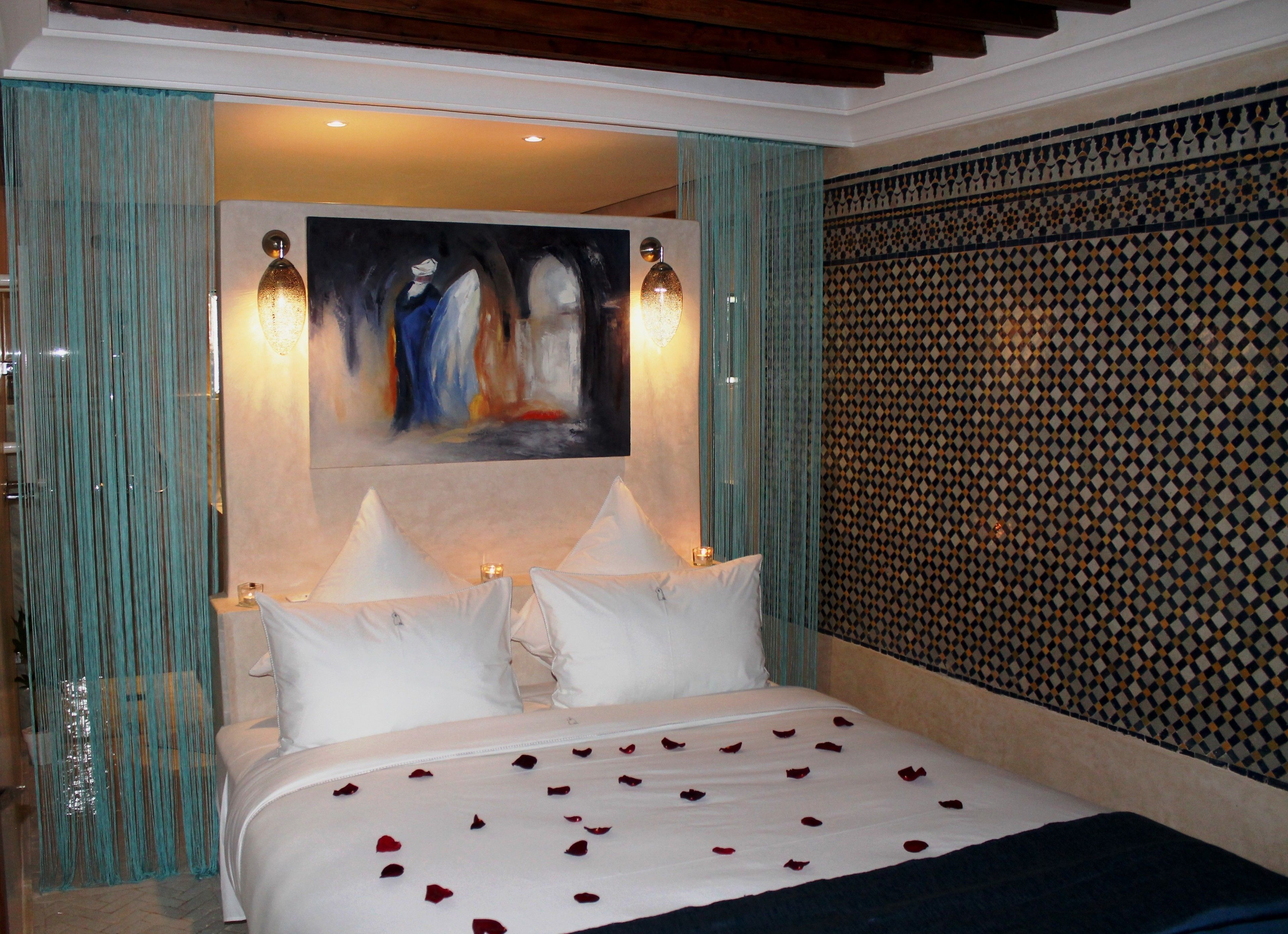 Une chambre d’hôtel avec un lit, deux lampes de chevet, un tableau au mur et un papier peint à motifs.