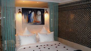 Une chambre d’hôtel avec un lit, deux lampes de chevet, un tableau au mur et un papier peint à motifs.