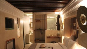 A hotel room with a bed, a television, a mirror, and a shower area. - Riad Kalaa 2 (Rabat)