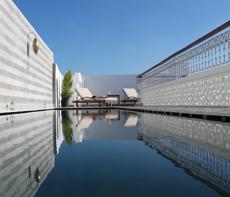 Una piscina al aire libre, sillones reclinables de piscina