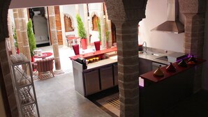 A modern kitchen with a central island, a dining area with chairs and tables, and a stone archway. - Riad Kalaa 2 (Rabat)