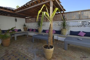 Un espacio al aire libre con mobiliario de mimbre y plantas en macetas.