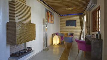 A modern living room with a fireplace, wooden ceiling, and a dining area with chairs and a table.