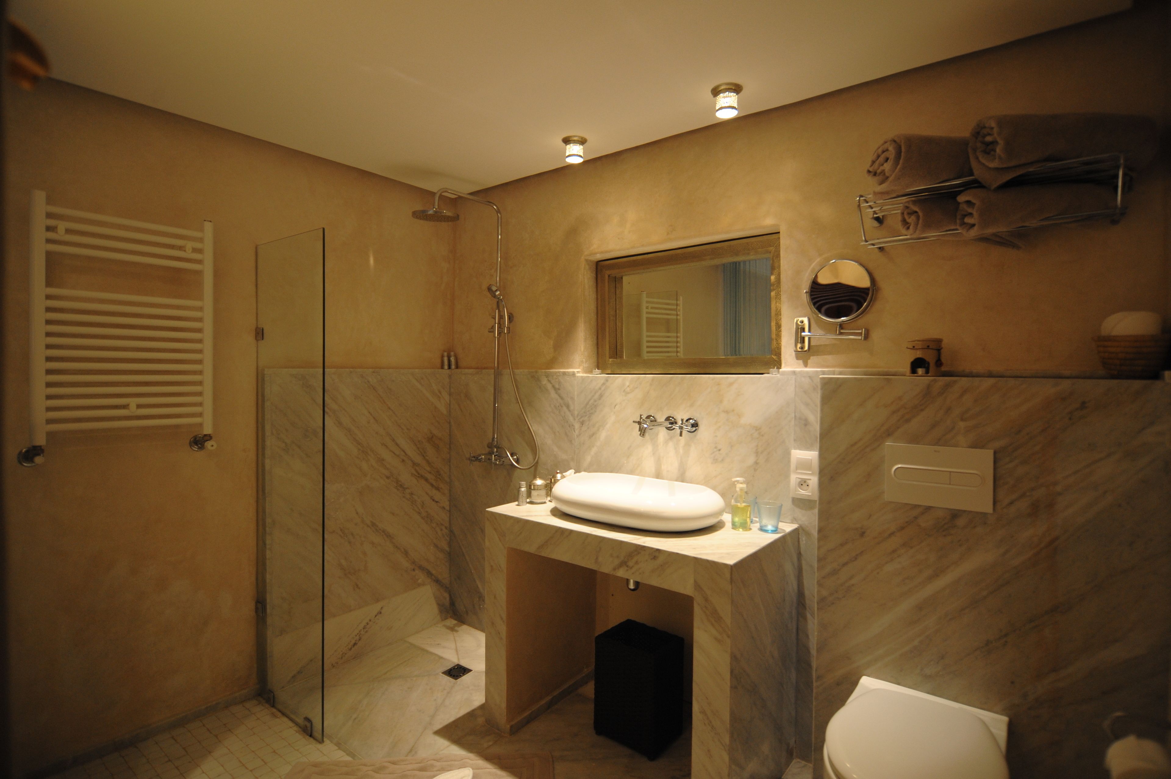 A bathroom with a glass-enclosed shower, a marble sink, and a toilet.