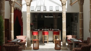 A courtyard with stone columns, a bar area, and striped chairs. - Riad Kalaa 2 (Rabat)