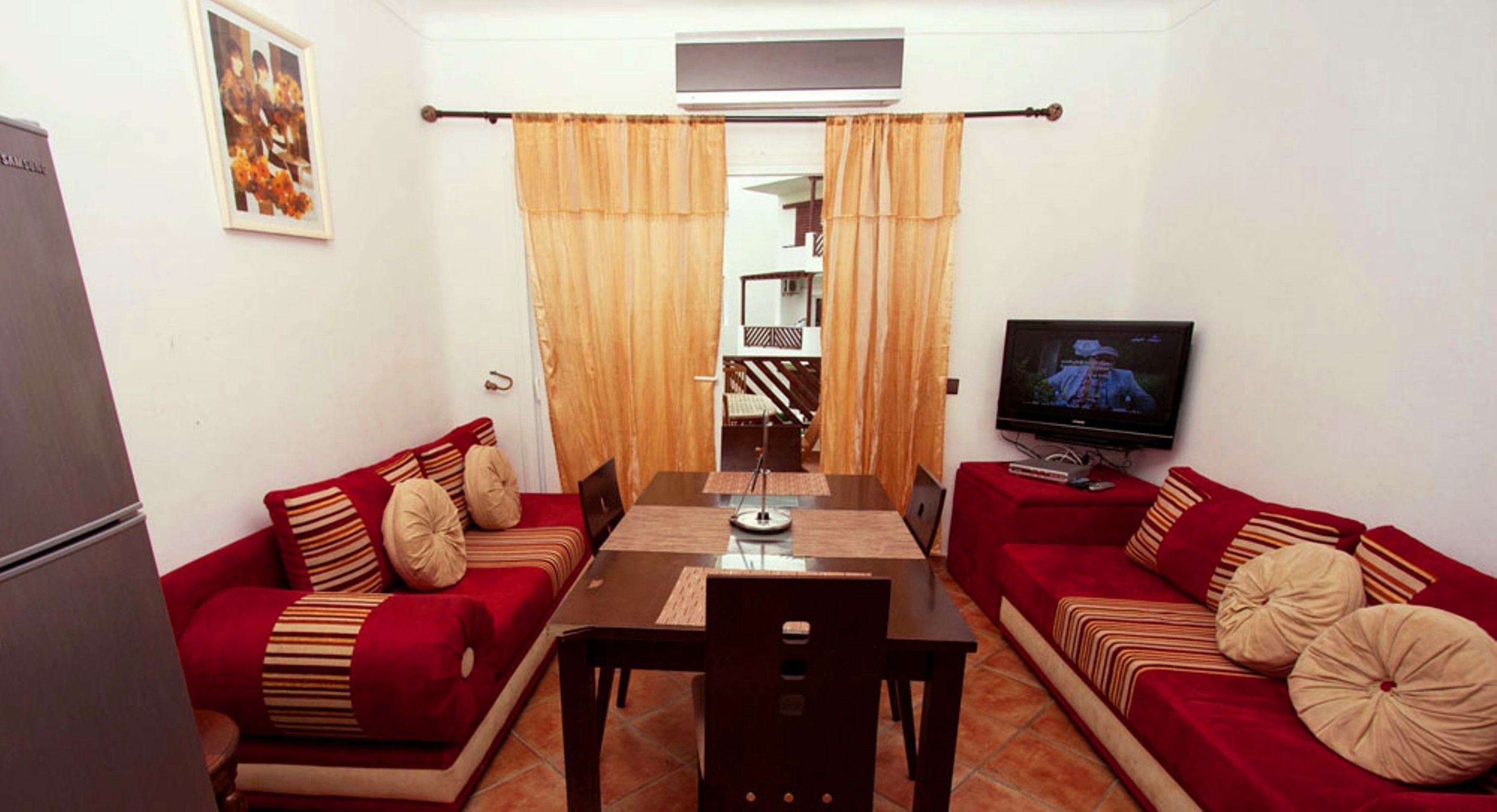 A compact living space with a dining table, two sofas, a TV, and a small kitchen area.