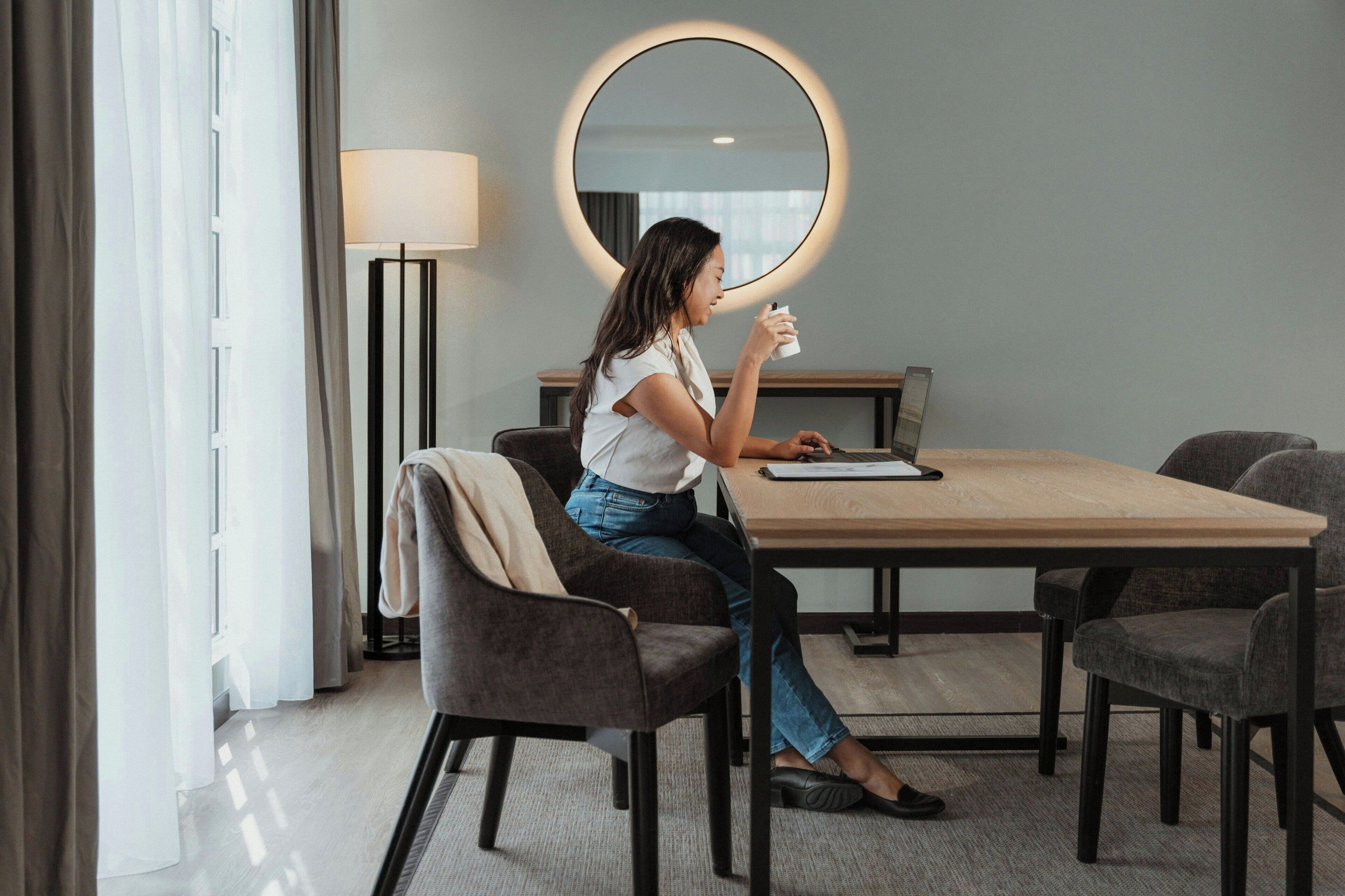 A hotel room with a round mirror, a desk, and a chair.