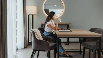 A hotel room with a round mirror, a desk, and a chair.