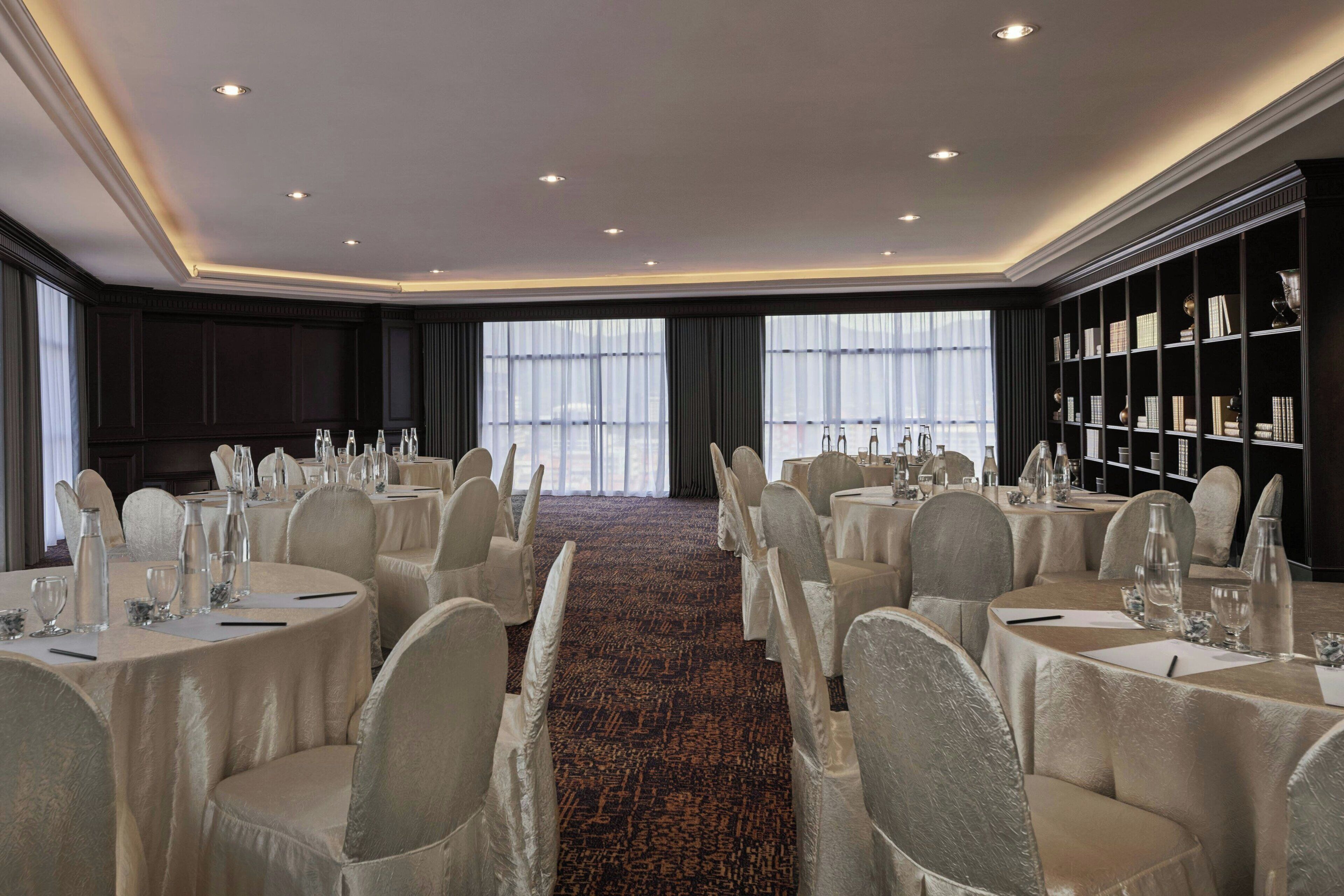 Une salle de banquet avec des tables rondes, des chaises et une bibliothèque.