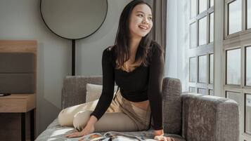 A person sitting on a sofa in a room with a large window, a round mirror on the wall, and a small table with a chair.
