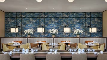 Un restaurante con varias mesas dispuestas para comer, cada una con vajilla blanca y sillas.