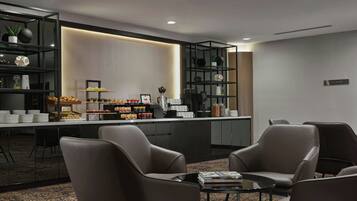 A modern hotel lobby with a reception desk, seating area, and shelves with amenities.