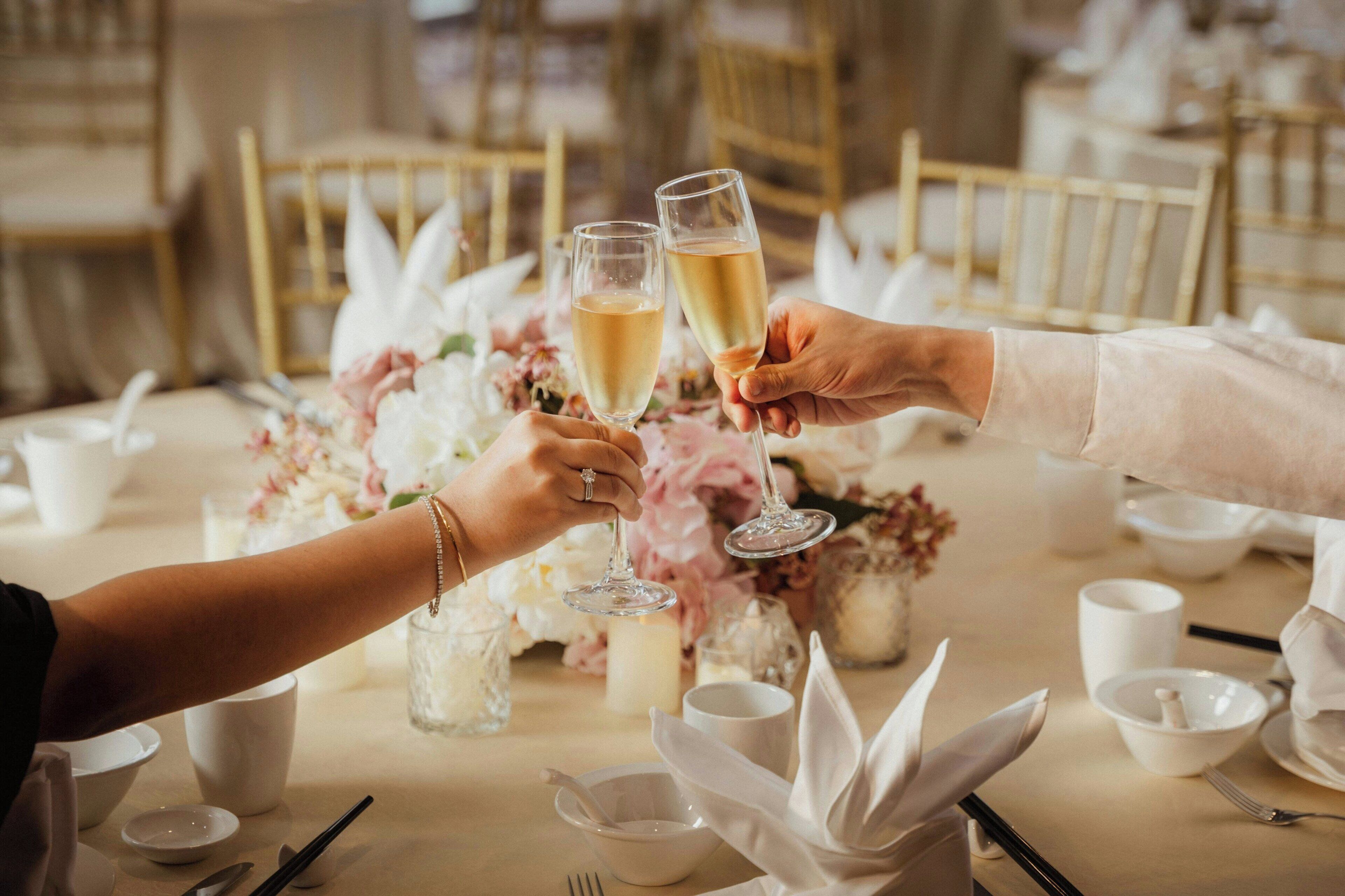 Mesa dispuesta para una ocasión de cena formal, con vajilla y cristalería blancos, y centros de mesa con flores.