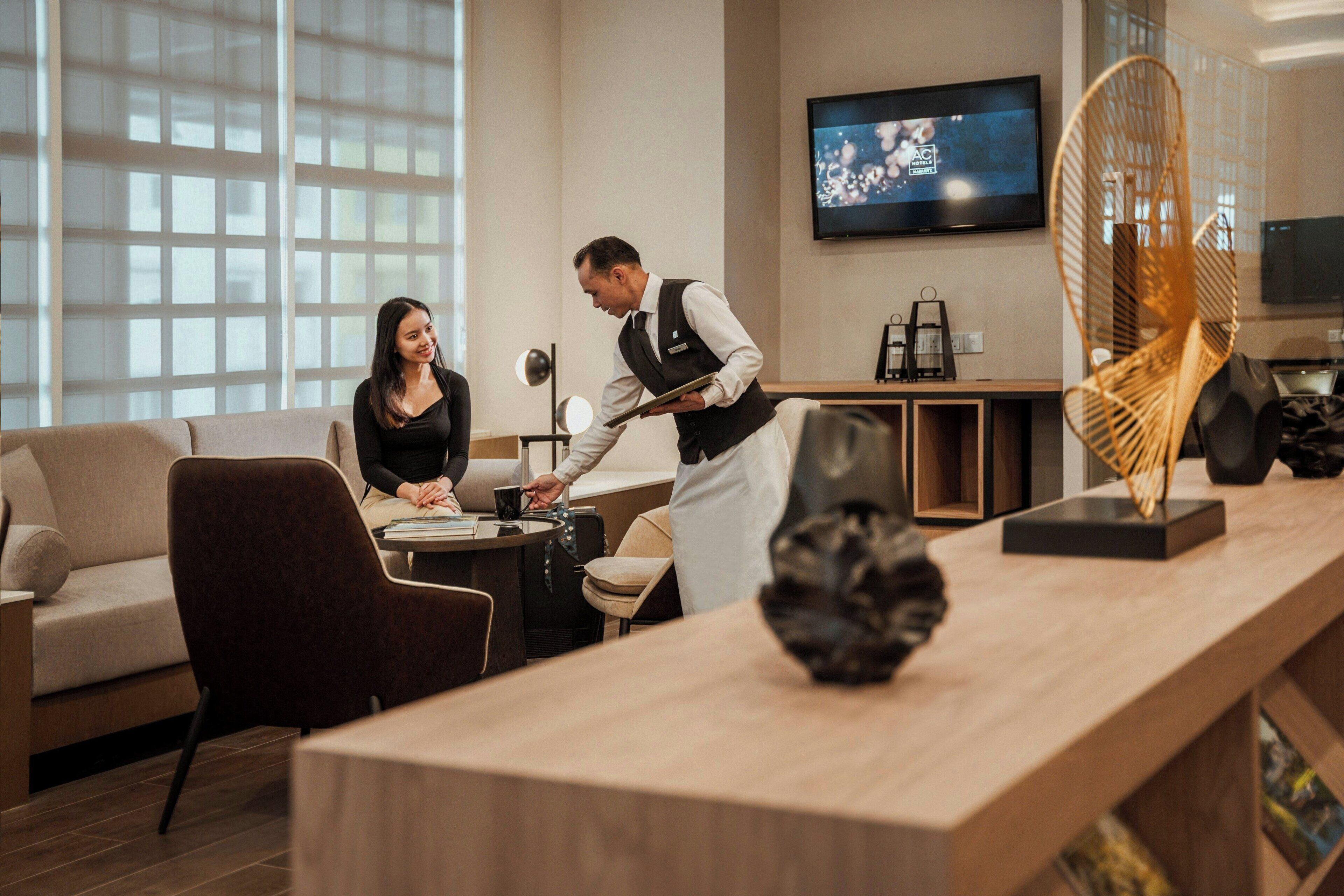 Un hall d’hôtel moderne avec un comptoir d’accueil, un canapé et un téléviseur fixé au mur.