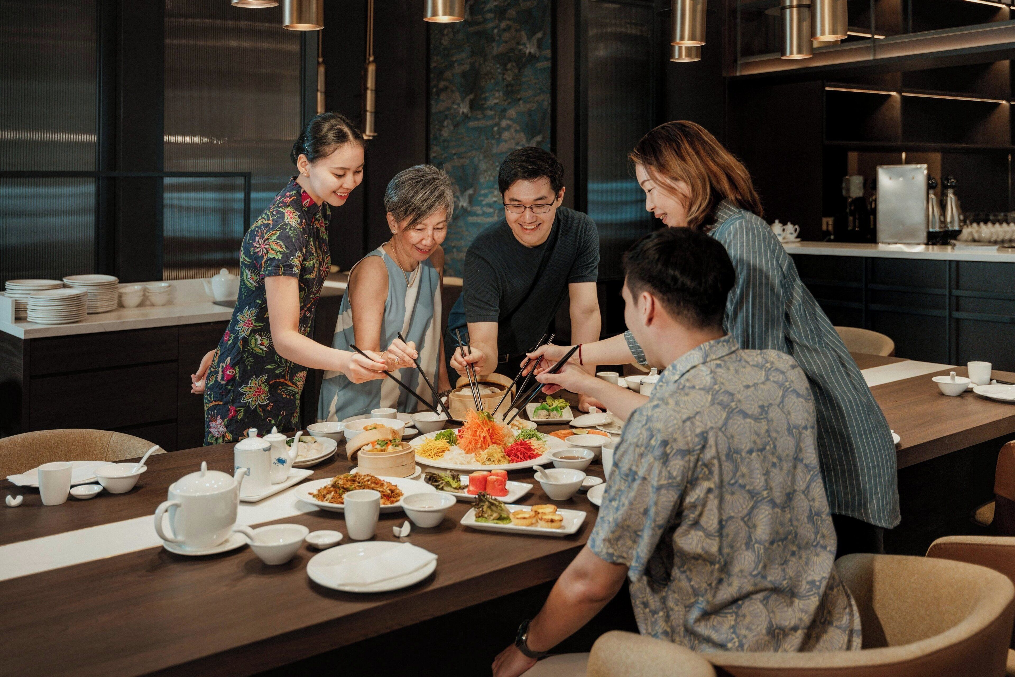 A group of people dining at a long table in a modern restaurant with a dark interior and contemporary decor.