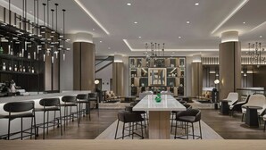A modern hotel lobby with a central bar area, seating arrangements, and a large decorative wall.