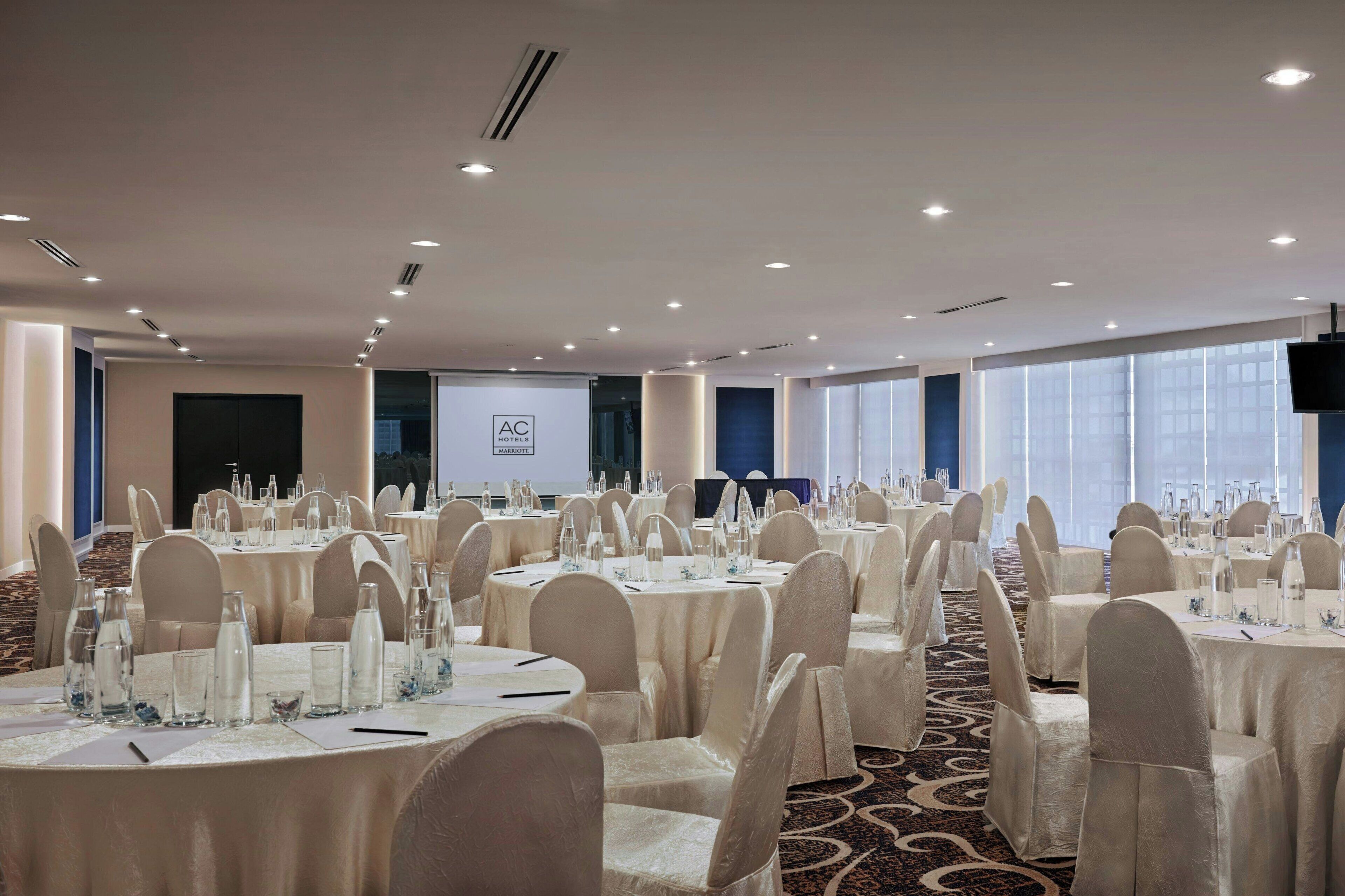 A conference room with round tables, chairs, and a projection screen.