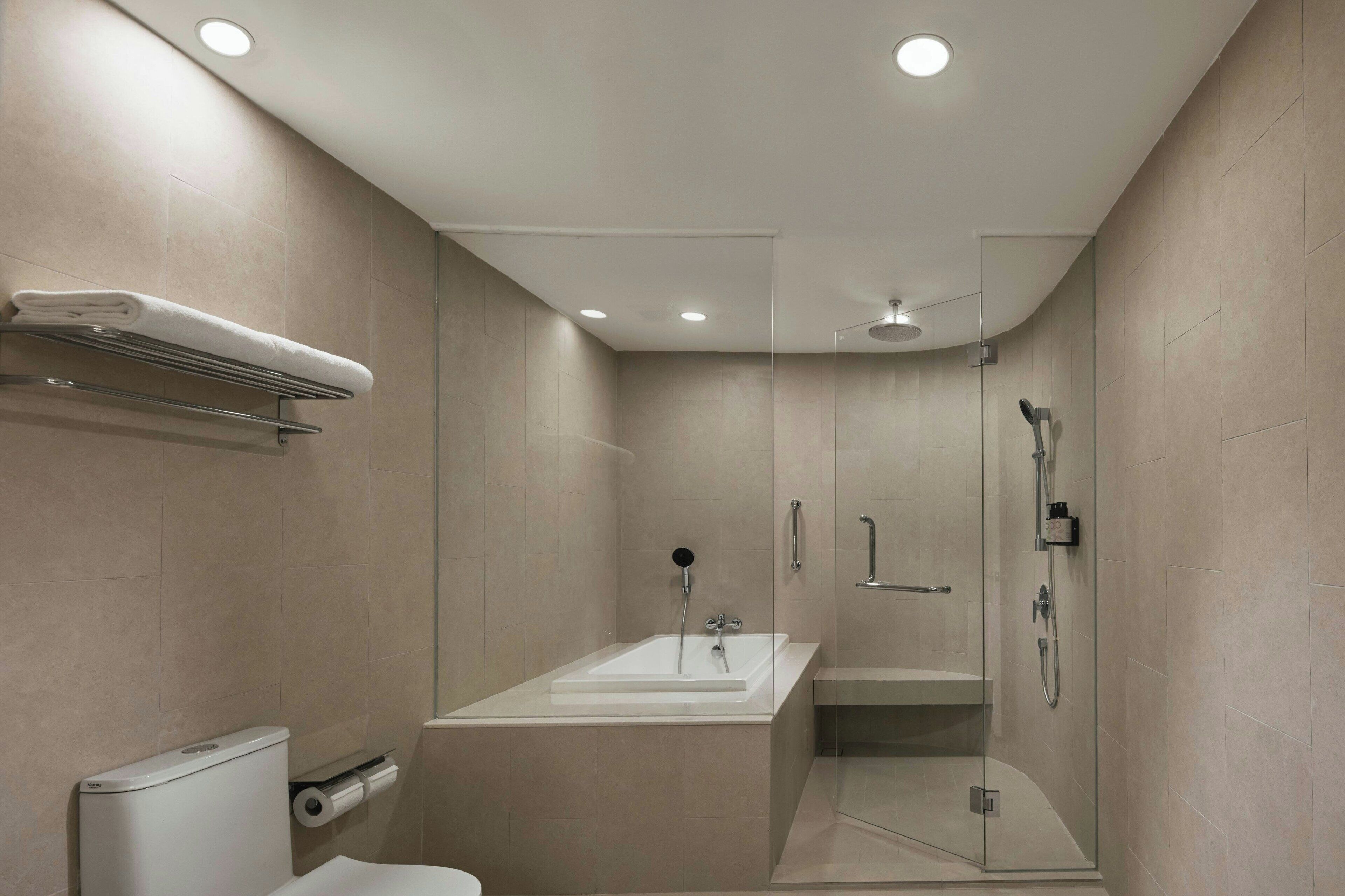 A modern bathroom with a glass-enclosed shower, a white bathtub, and a towel rack.