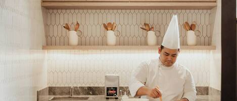 A chef in a modern kitchen with wooden cabinets and a marble countertop.