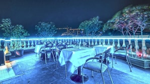 An outdoor dining area with tables and chairs, a railing, and potted plants. - Zain International Hotel (Dubai)
