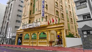 A hotel with a prominent sign, multiple windows, and a red awning. - Zain International Hotel (Dubai)