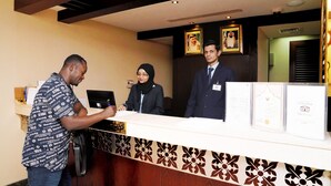 A reception desk with a patterned border, framed certificates, and two portraits on the wall. - Mark Inn Hotel Deira (Dubai)