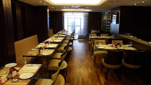 A restaurant with long tables set for dining, wooden flooring, and a view through a patterned window. - Mark Inn Hotel Deira (Dubai)