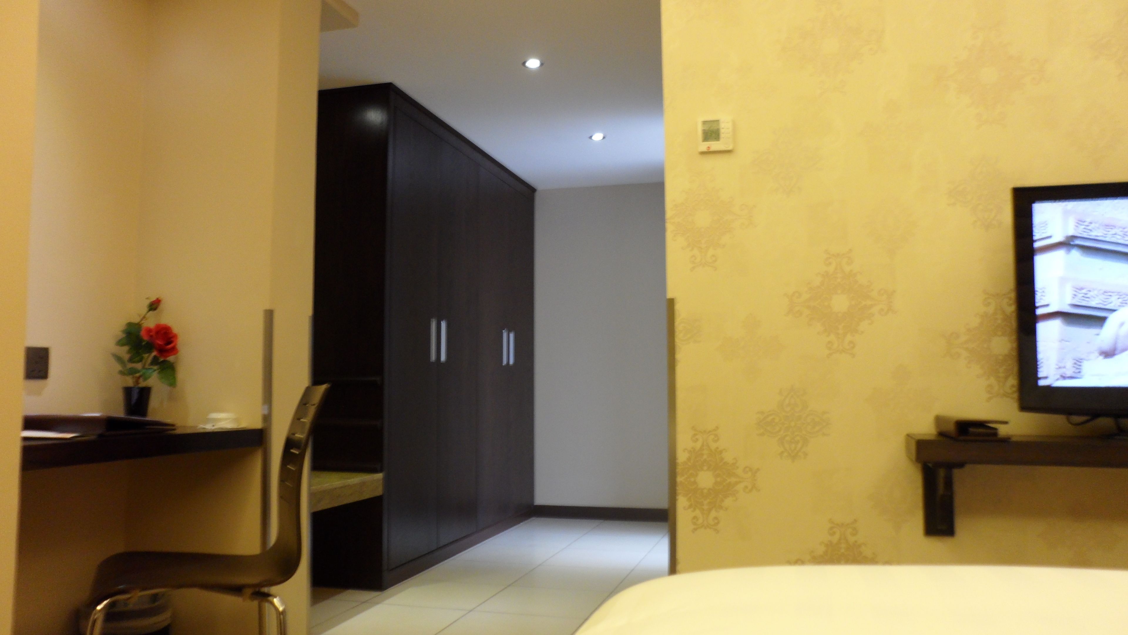 Ein Hotelzimmer mit einem Bett, einem Schreibtisch mit Stuhl, einem Fernseher und einem Kleiderschrank.