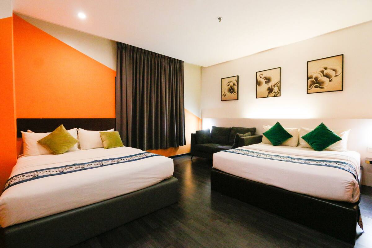 A hotel room with two beds, a sofa, and a large window with curtains.