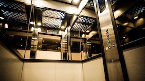 An elevator interior with a metallic finish, glass panels, and a control panel with floor indicators. - Golden Roof Hotel Ampang Ipoh (Ipoh)