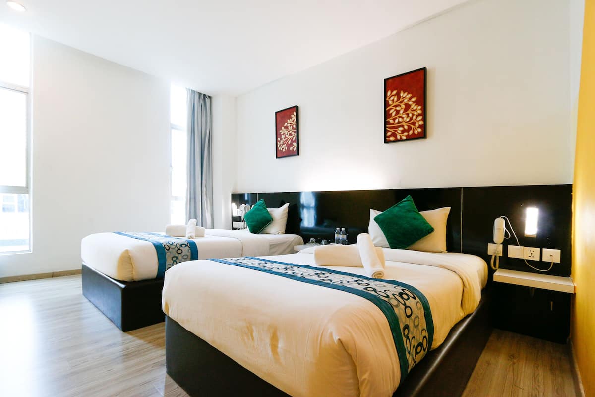A hotel room with two beds, a flat-screen TV, a bedside table with a phone, and artwork on the walls.