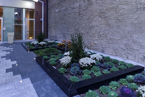 A landscaped garden with various plants and a paved walkway leading to a building entrance. - Holiday Inn New York City - Times Square by IHG (New York)