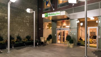 A Holiday Inn hotel entrance with a brick facade, glass doors, and a sign above the entrance.