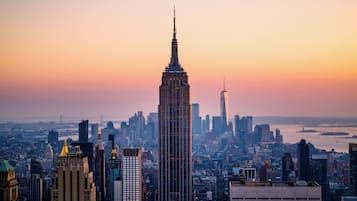 A cityscape with a prominent skyscraper, likely the Empire State Building, surrounded by other high-rise buildings.