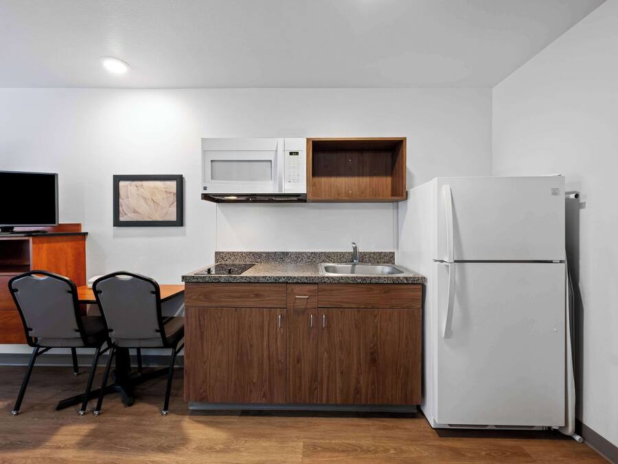 A compact kitchen with a microwave, refrigerator, and wooden cabinets.