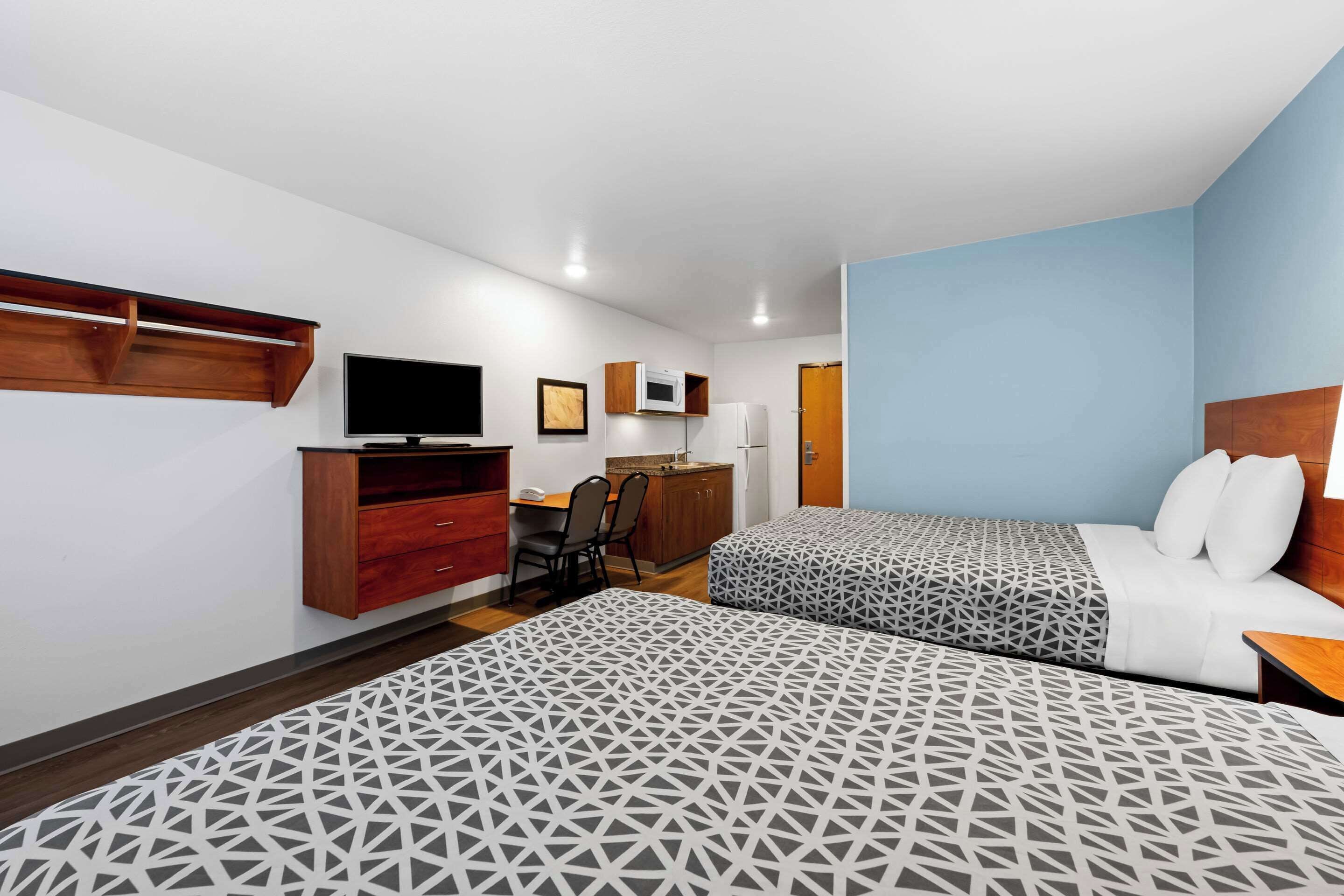 A hotel room with two beds, a desk, a TV, and a wardrobe.