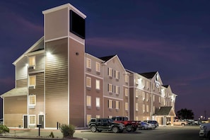 A multi-story hotel with a modern design, featuring a central entrance and multiple parking spaces. - WoodSpring Suites Hobbs (Hobbs)