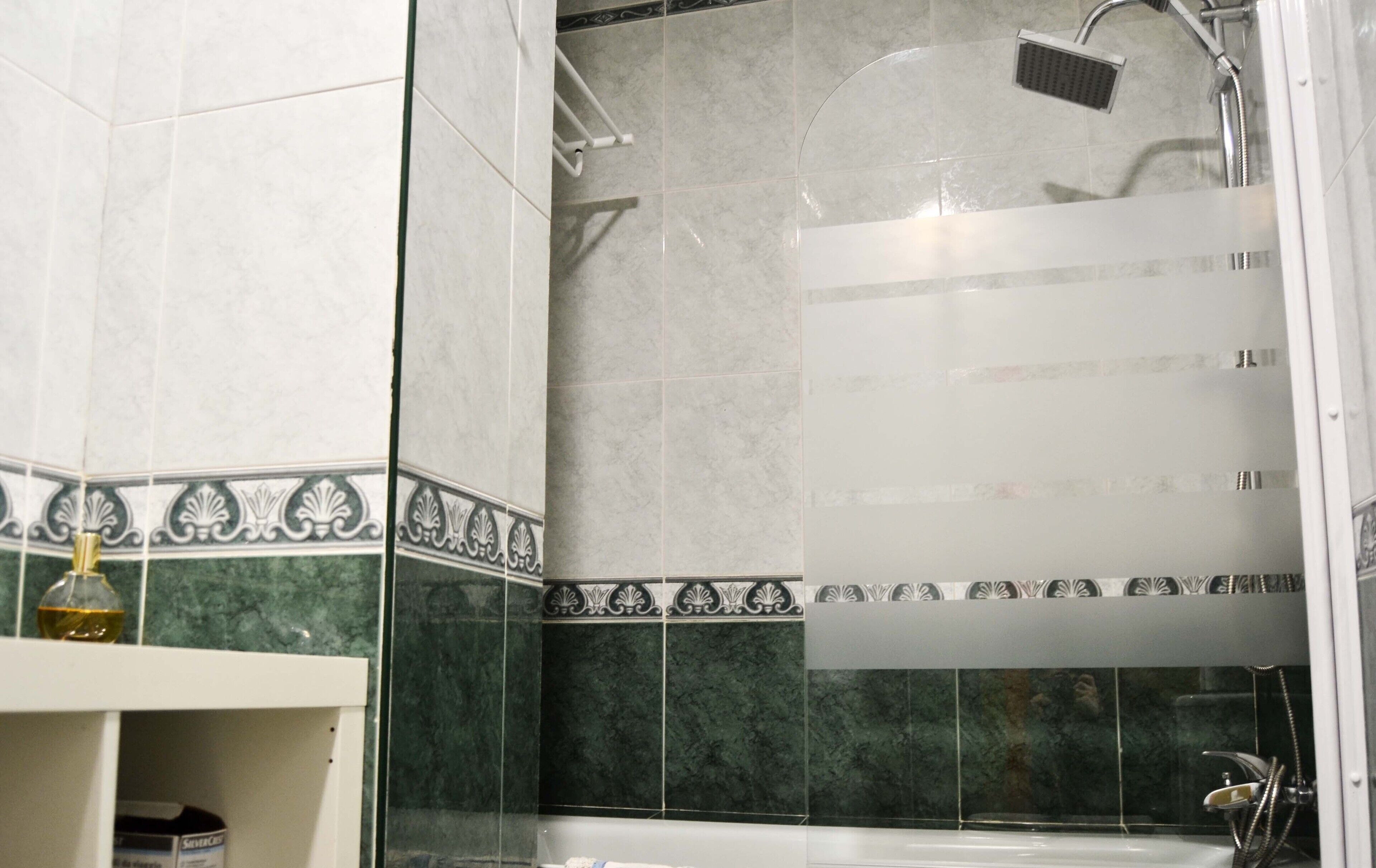 Ein Badezimmer mit Dusche, Waschbecken und Ablage für Toilettenartikel.