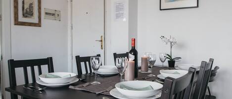 A dining table set with plates, glasses, and cutlery, a candle, and a bottle of wine.