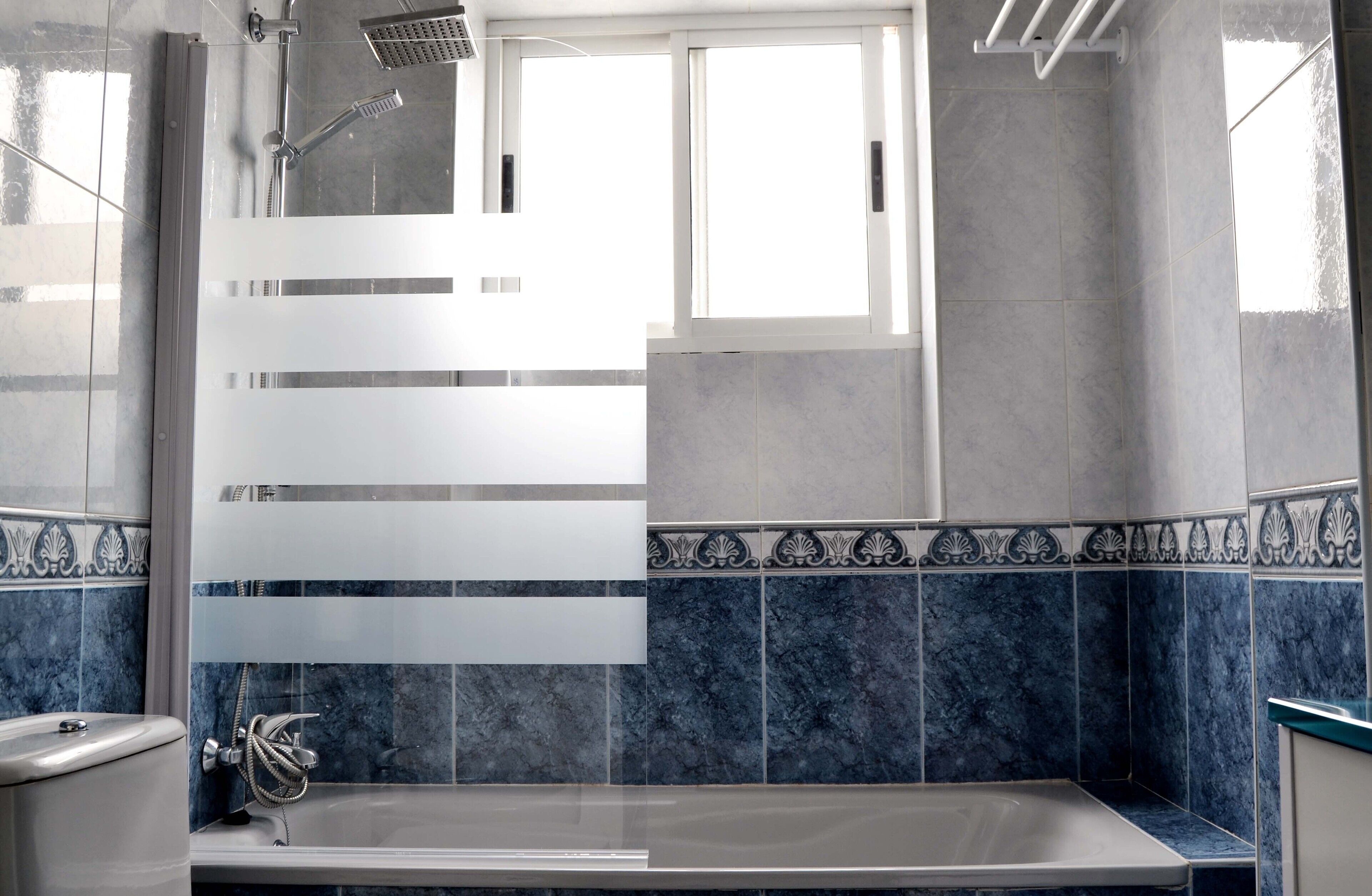 Un baño moderno con bañera, ducha y ventana.