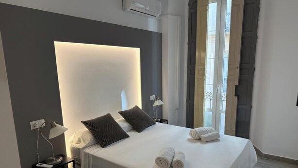 Un hotel moderno con una cama grande, lámparas de noche, una mesita de noche y vistas al exterior.