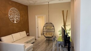 Una sala de estar moderna con un sofá, una silla colgante, un escritorio con una computadora y un aire acondicionado instalado en la pared.