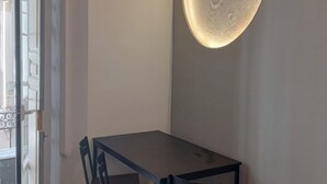 Comedor con mesa y sillas, lámpara de pared y equipo de aire acondicionado.