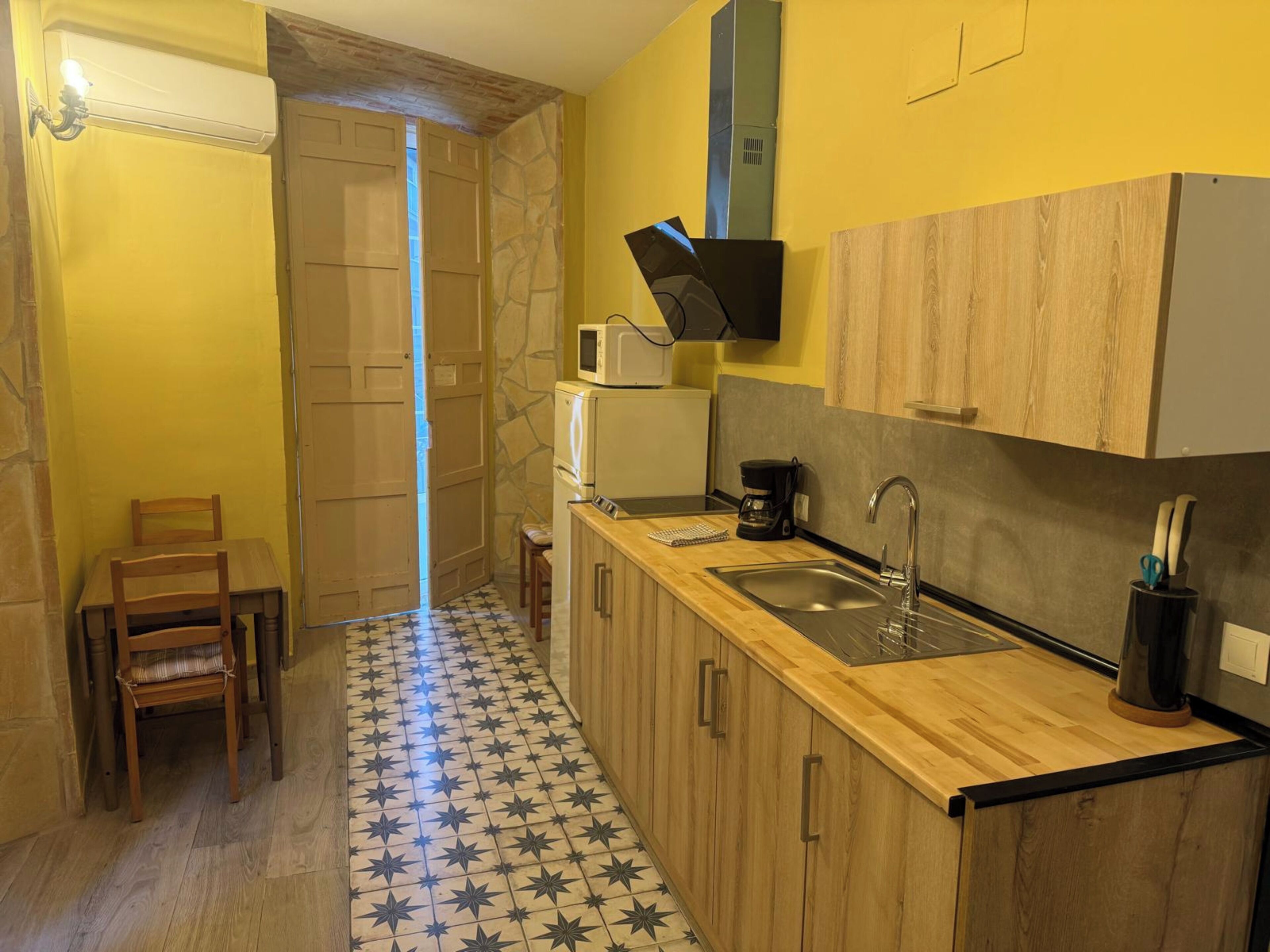 Una cocina compacta con microondas, cafetera y lavamanos.